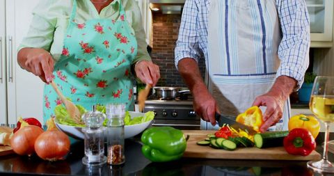 Senior Couple Chopping Vegetables Together in Modern Kitchen