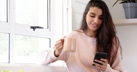 Woman Enjoying Coffee and Smartphone by Bright Window