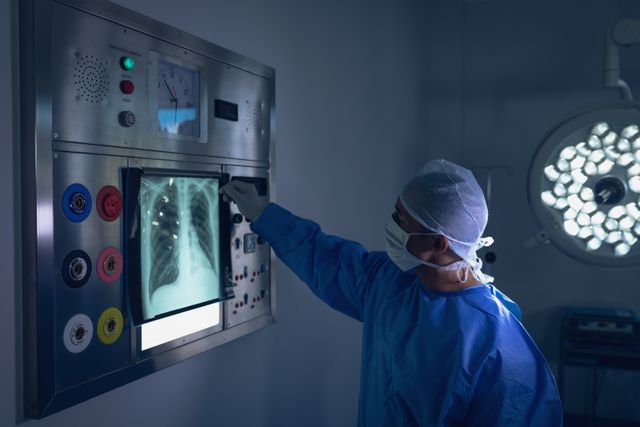 Male surgeon examining x-ray report on x-ray light box in operation theater in hospital