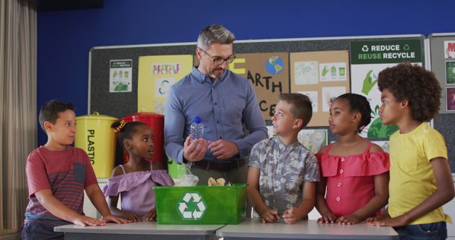 Teacher is explaining recycling to engaged schoolchildren in a classroom. School recycling bins and educational posters about recycling are in the background. This is perfect for use in educational materials, articles about environmental practices in schools, and promotional content on sustainability in education.