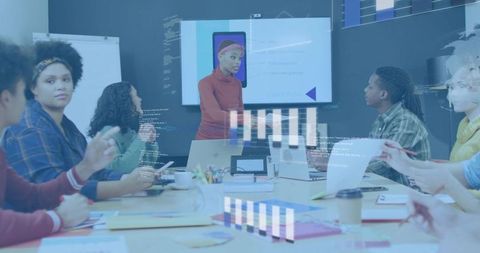 Team collaborating around table with presenter showing smartphone mockup and data charts