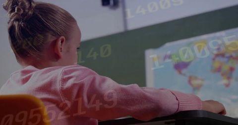 Young girl learning at desk in classroom with world map