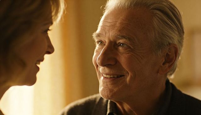 Smiling senior man gazing at partner in warm sunlit living room close-up, intimate portrait