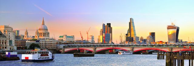 This panoramic view showcases the iconic London skyline during sunset, with the River Thames in the foreground. Prominent skyscrapers and historical buildings complement each other, offering a blend of modern and classic architecture. Perfect for travel advertisements, city guides, and editorial content related to London or urban landscapes.