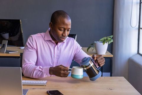 Professional Worker Pouring Coffee at Modern Office Desk