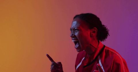 Shouting woman pointing finger in bold red jacket against gradient studio background