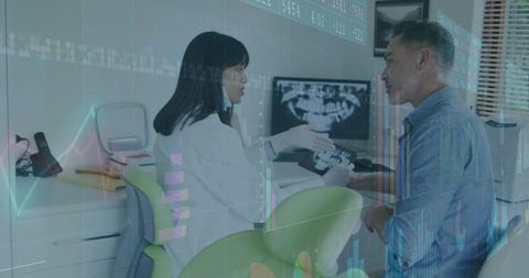 Dentist pointing at digital panoramic x-ray during patient consultation with data overlay