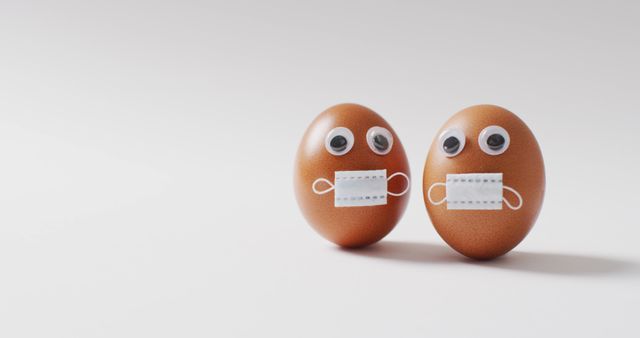 Image of eggs with eyes and face masks on a white surface. seasonal easter traditional sweet treats during covid 19 pandemic.