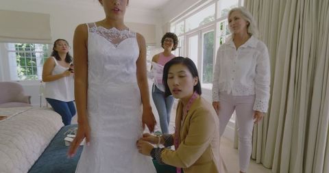 Bride Fitting Wedding Dress with Friends and Designer's Assistance