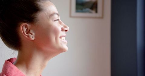 Teenager Smiling While Looking Out Window with Joy