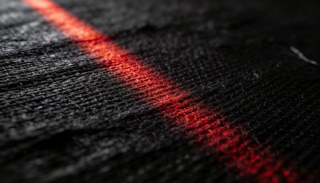 Glowing narrow red light band casting specular highlights across textured black fabric