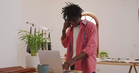 African american craftsman in workshop on laptop and phone call