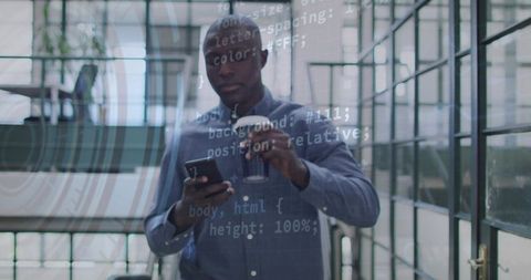 Black developer checking code on smartphone while holding coffee in modern office