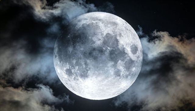 Full moon glowing through veiled clouds over starfield, detailed lunar surface and craters