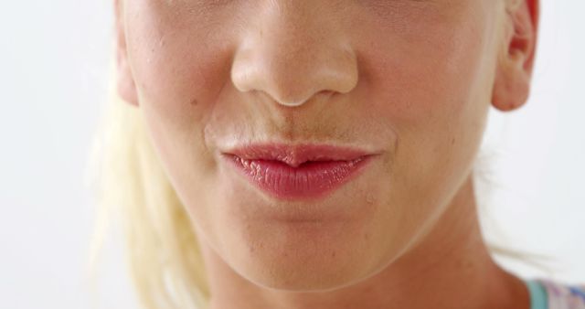 A close-up of a Caucasian woman's mouth, with copy space. Her lips are gently closed, and the focus on her mouth suggests a theme of beauty or speech.