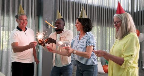 Diverse colleagues celebrating with sparklers in office lounge