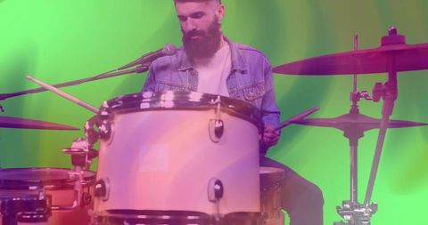 Bearded Drummer Performing on Stage with Microphone