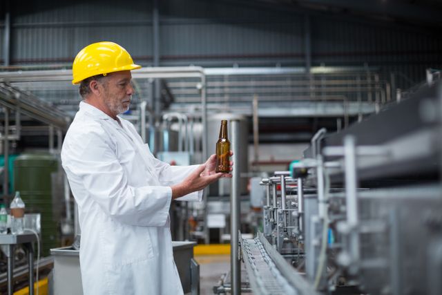 Attentive factory worker examining a bottle in factory
