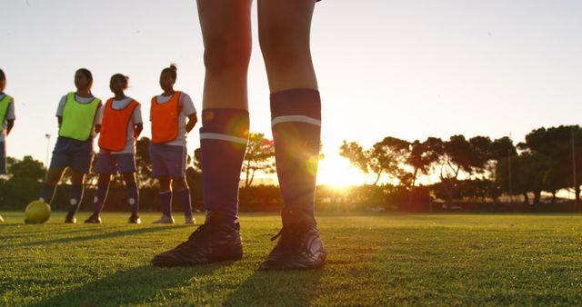 Legs of female football player standing with team on sunny sports field. Active lifestyle, sport, competition, hobby and wellbeing, teamwork, unaltered.