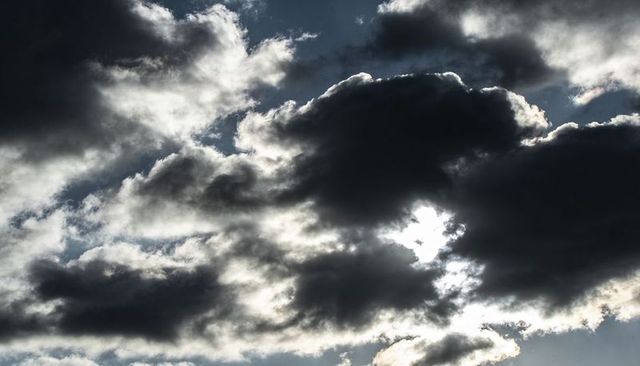 Sun peeking behind dramatic backlit storm clouds with silver lining and light rays