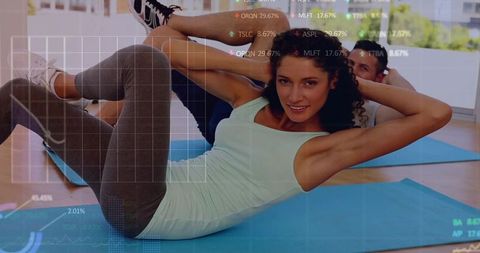 Woman performing bicycle crunches on blue mat with partner in studio, data overlay