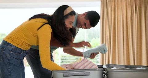 Young couple packing suitcase together with excitement