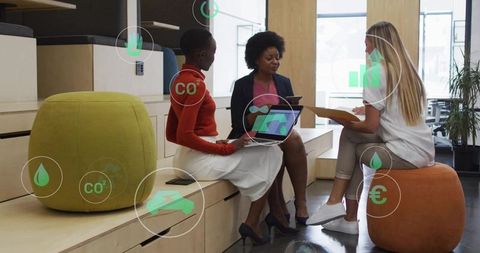 Businesswomen collaborating in open office lounge with sustainability analytics overlays