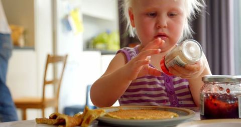 Curious Toddler Holding Pepper Shaker Near Pancakes in Kitchen