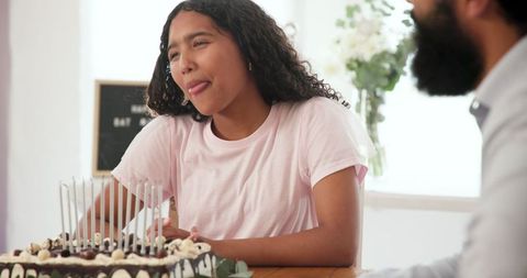 Teen girl celebrating birthday with cake and candles at home
