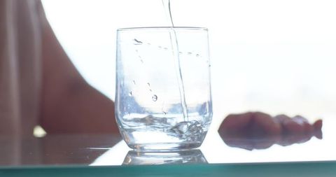 Pouring Water into Glass on Reflective Table Minimalist High-Key Kitchen Lifestyle