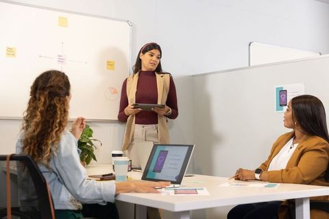 Multicultural women presenting tablet-led project and brainstorming in modern office