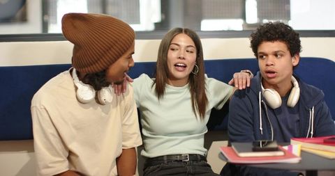 African american students leaning, discussing and studying together in campus lounge