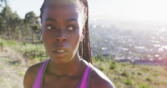 African american woman exercising outdoors putting on wireless earphone in countryside at sunset. healthy outdoor lifestyle fitness training.