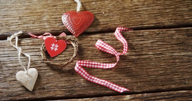 A rustic wooden surface features a variety of heart-shaped decorations, including a woven heart and a red heart with a floral pattern, with copy space. These charming ornaments symbolize love and are often used in festive or romantic decor settings.