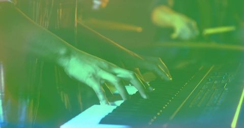 Musician Playing Synthesizer on Stage with Vibrant Green Lighting