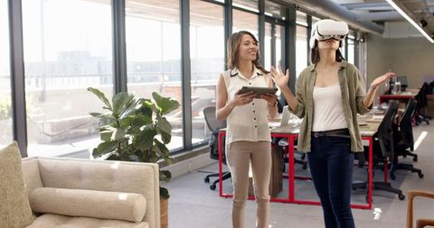 Female colleagues engaged with vr technology in modern office