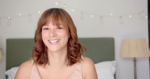Biracial Woman Smiling in Cozy Bedroom Setting