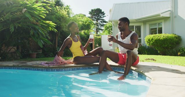 Couple relaxing by poolside, enjoying a refreshing summer drink, bonding and laughing together in a tropical outdoor setting. Perfect for use in advertisements, travel brochures, lifestyle blogs, or vacation promotions highlighting relaxation, leisure, and tropical atmospheres.