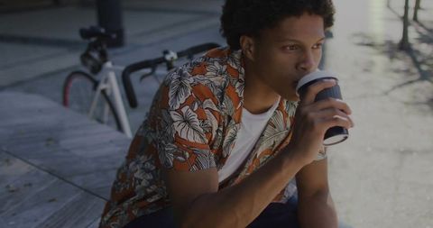 Young Man Relaxing with Coffee Near Urban Bike Rack