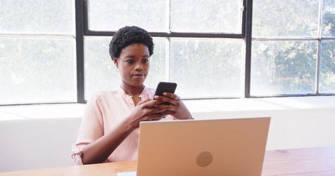 Focused Businesswoman Balancing Work on Laptop and Phone