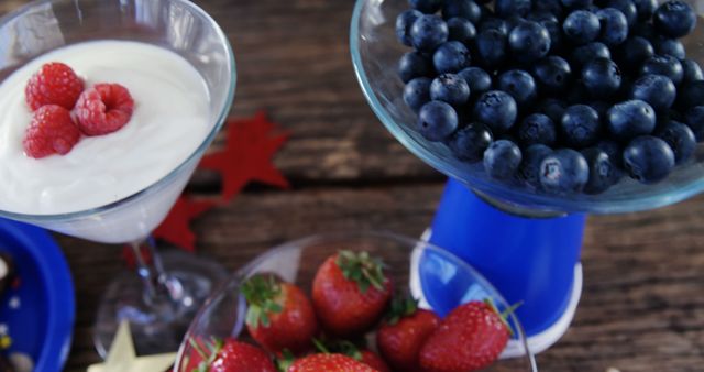 A selection of fresh berries and yogurt offers a healthy snack option, with copy space. Blueberries, raspberries, and strawberries are presented in elegant glassware, adding a touch of sophistication to the nutritious fare.