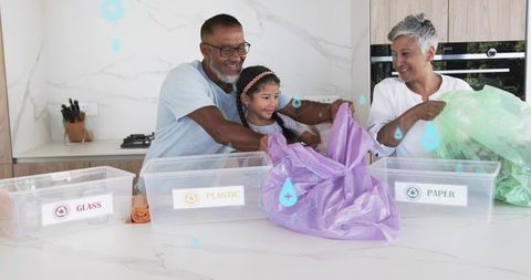Multi-generational family sorting recyclables in kitchen, teaching kid sustainable habits