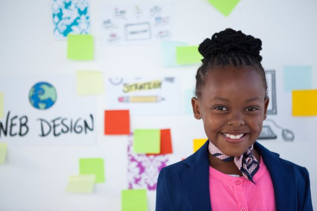 Young businesswoman smiling confidently in an office environment with sticky notes and a whiteboard in the background. Ideal for use in articles about young entrepreneurs, business planning, creativity in the workplace, and leadership skills in children.