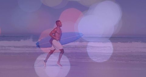 Running surfer carrying blue surfboard on beach with purple-pink bokeh overlay