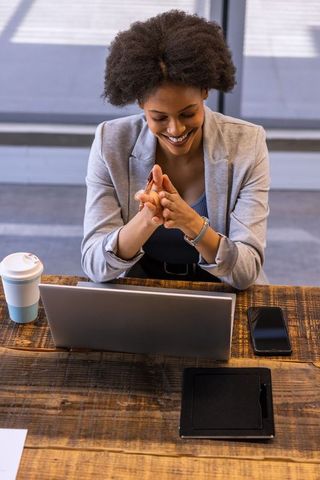 Confident Businesswoman Smiling While Engaging with Laptop in Modern Workspace