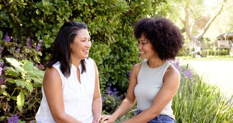Women enjoying a serene moment together. Suitable for themes of family bonding, happiness, and outdoor living. Ideal for illustrating family relationships, personal blogs, lifestyle articles, or mental wellness promotions. Vivid greenery adds a vibrant backdrop for positive messaging.