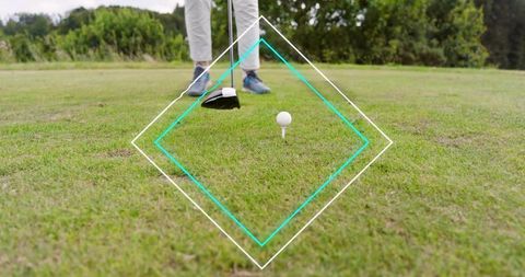 Senior golfer lining up driver over tee on fairway with blue shoes, focused stance