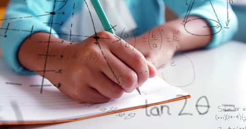 Student writing math equations using green pencil close-up of hand on ruled notebook