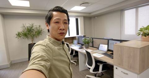 Professional taking selfie in modern office workspace surrounded by technology