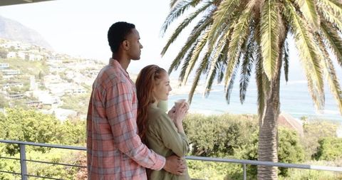 Peaceful couple embracing on scenic balcony overlooking ocean views